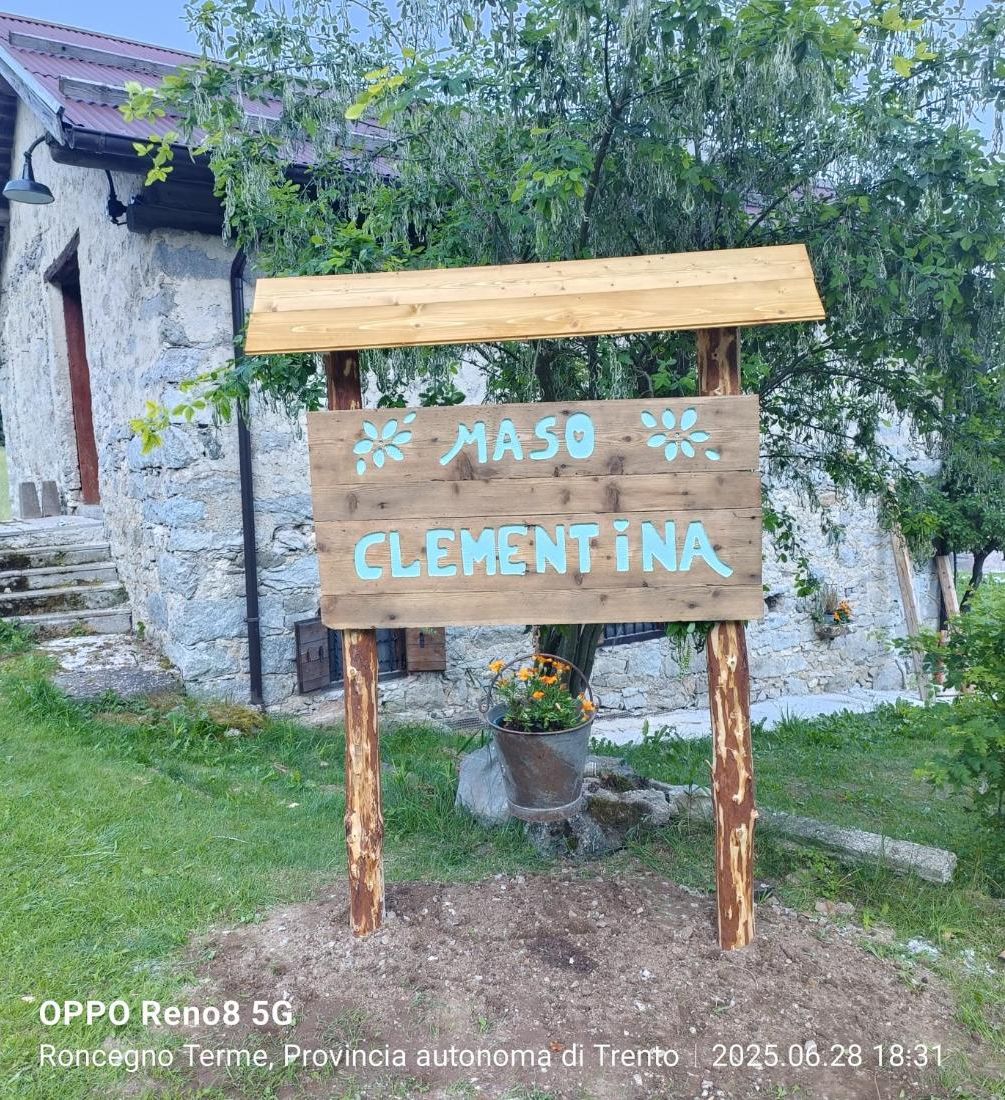 A rustic stone building with a wooden signboard reading 'MASO CLEMENTINA' in front.