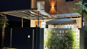 Un espace extérieur abrité, doté d’un portail en métal, d’une clôture en bois et de plantes en pot.
