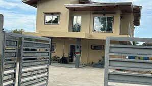 Un immeuble de deux étages avec une façade beige, de grandes fenêtres et une entrée fermée par un portail.