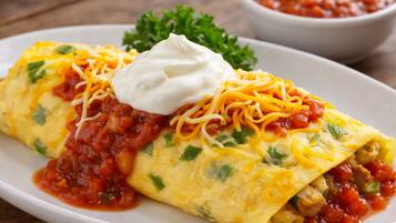 Un plato de enchiladas con queso y crema agria, adornado con perejil, sobre una mesa de madera.