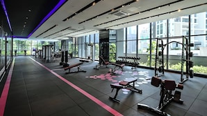Ein modernes Fitnessstudio mit unterschiedlichen Trainingsgeräten, großen Fenstern und Blick auf umliegende Gebäude.