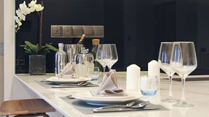 Eine moderne Küche mit Marmorarbeitsplatte, weißen Schränken und einer Kochinsel mit Barhocker.