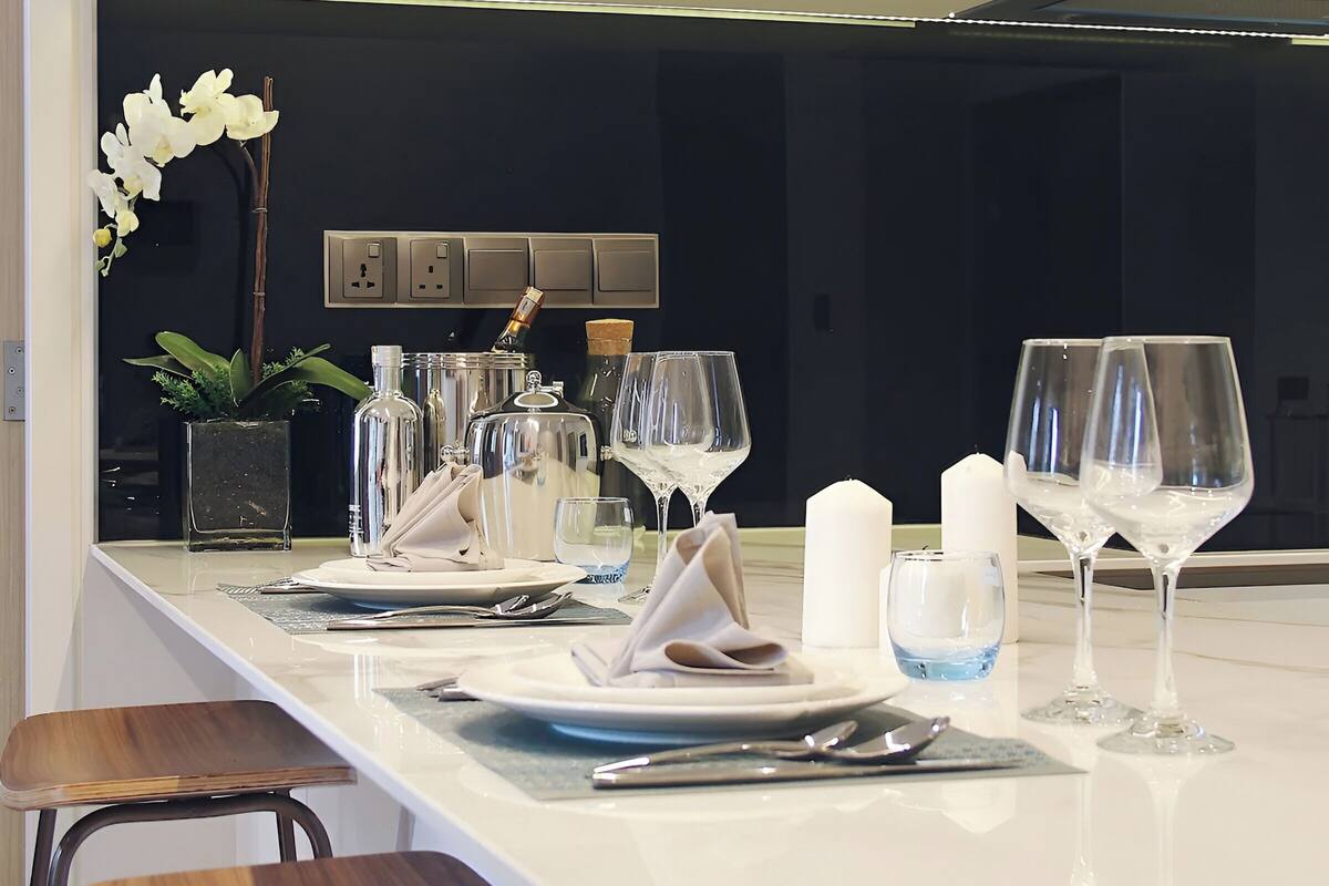 A modern kitchen with a marble countertop, white cabinets, and a central island with bar stools.
