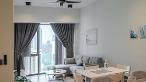 Ein modernes Wohnzimmer mit einer Couch, einem Esstisch und Stühlen. Ein Deckenventilator und Einbaulampen sind vorhanden.