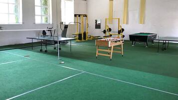 Eine Sporthalle mit Tischtennisplatte, Kicker und Gewichthebern.