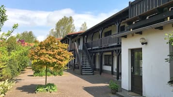 Ein Innenhof mit einem Backsteinweg, einem Baum und einem Gebäude mit Balkon und Treppe.