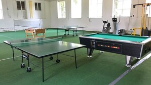A billiards room with two pool tables, a foosball table, and a table tennis table.