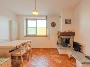 A dining area with a table and chairs, a fireplace, and a window with curtains.