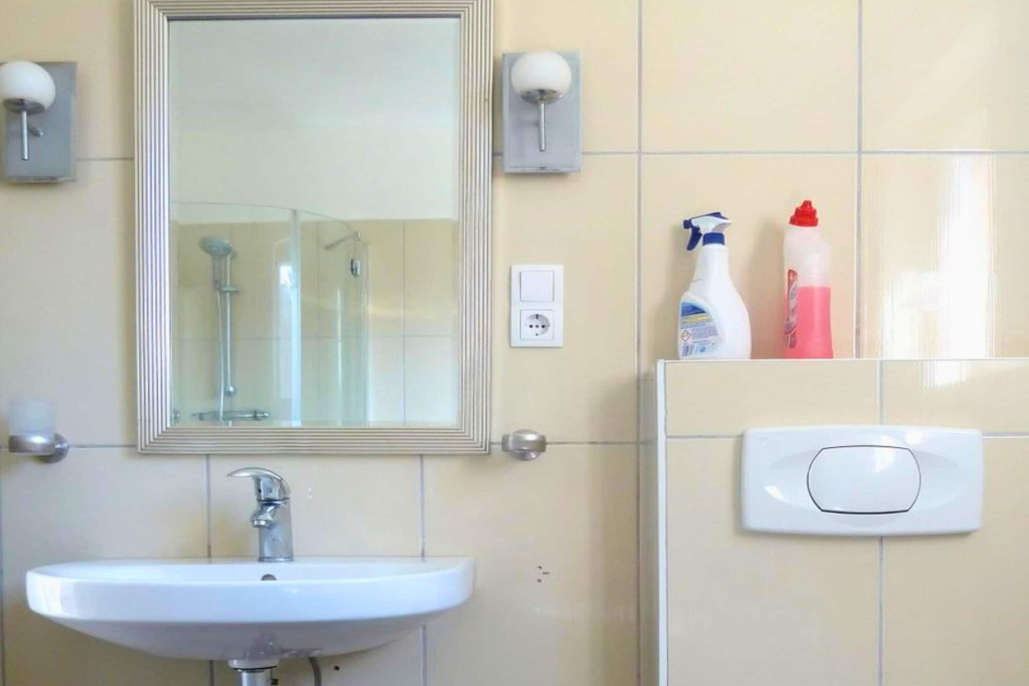 Een badkamer met een wit wastafelmeubel, een spiegel en twee wandlampen.