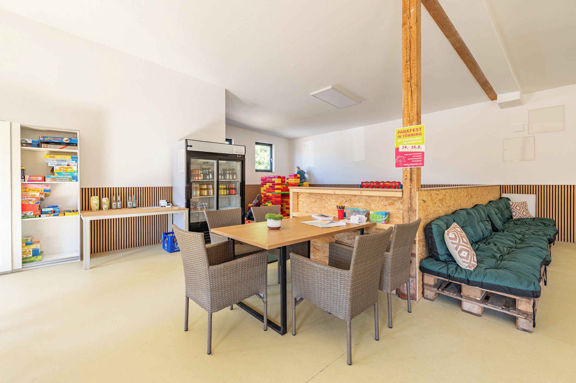 Um quarto com mesa de jantar, cadeiras, geladeira e um sofá.
