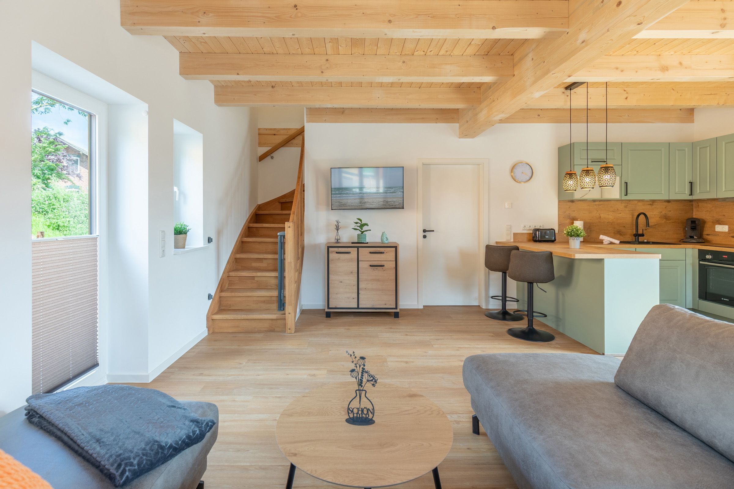 Una sala de estar moderna con un sofá, una mesa de centro y una escalera que lleva a una cocina.
