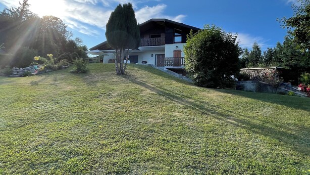 A two-story house with a sloped roof, a balcony, and a well-maintained lawn. - Magnificent apartment overlooking the Vallée Verte (Habère-Lullin)