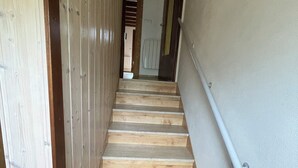 A wooden staircase with a handrail, leading to a room with a door and a window. - Magnificent apartment overlooking the Vallée Verte (Habère-Lullin)