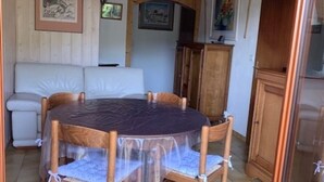 A dining area with a round table covered by a transparent tablecloth, surrounded by wooden chairs. - Magnificent apartment overlooking the Vallée Verte (Habère-Lullin)