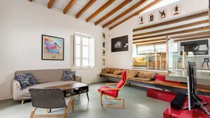 Ein modernes Wohnzimmer mit einer Couch, Sesseln, einem Couchtisch und Kunstwerken an den Wänden.