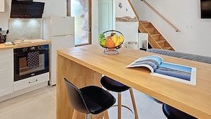 A modern kitchen with a wooden ceiling, a central island with bar stools, and a fruit bowl.