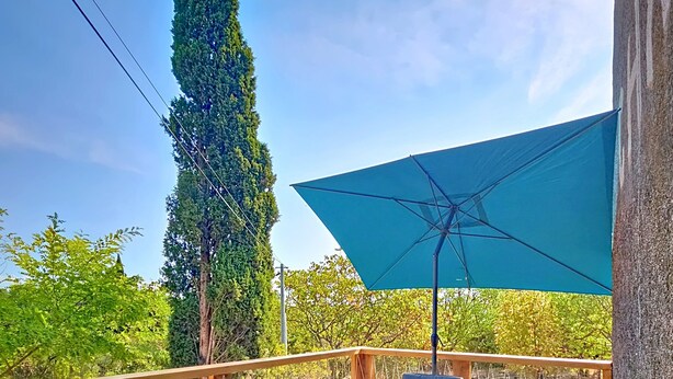 A wooden deck with wicker furniture, a table with food, and a large umbrella.