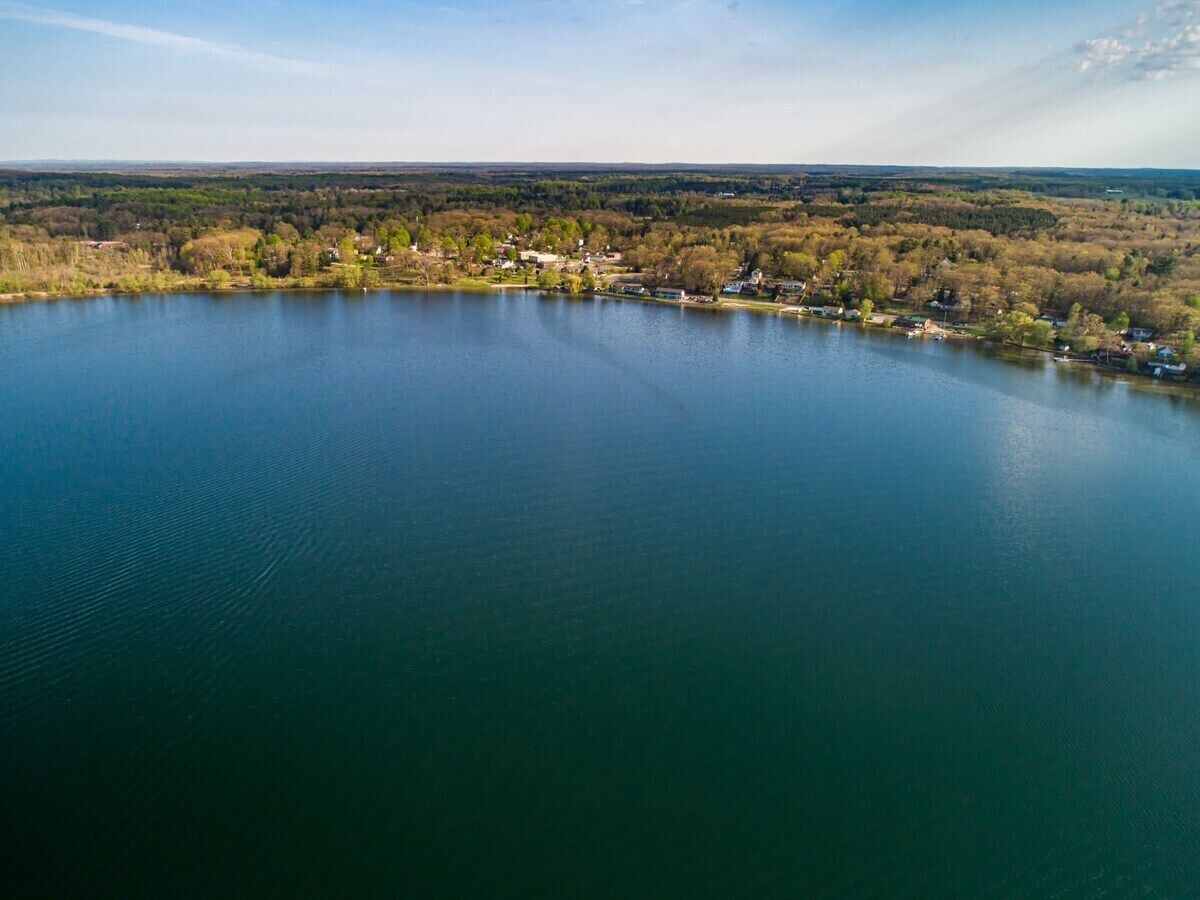 An aerial view of a lake surrounded by a forested area with houses along the shore.