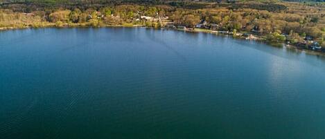 An aerial view of a lake surrounded by a forested area with houses along the shore.