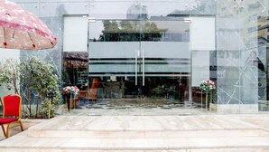 Een moderne gevel met glas, een rode stoel en een bloemstuk.