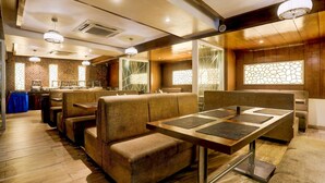 Een restaurant met houten vloeren, beklede zittingen en een centrale tafel met tafelonderleggers.
