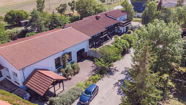 A two-story building with a red-tiled roof, a covered porch, and a car parked in front. - Landpension Dubnitz, double room 5 (Sassnitz)