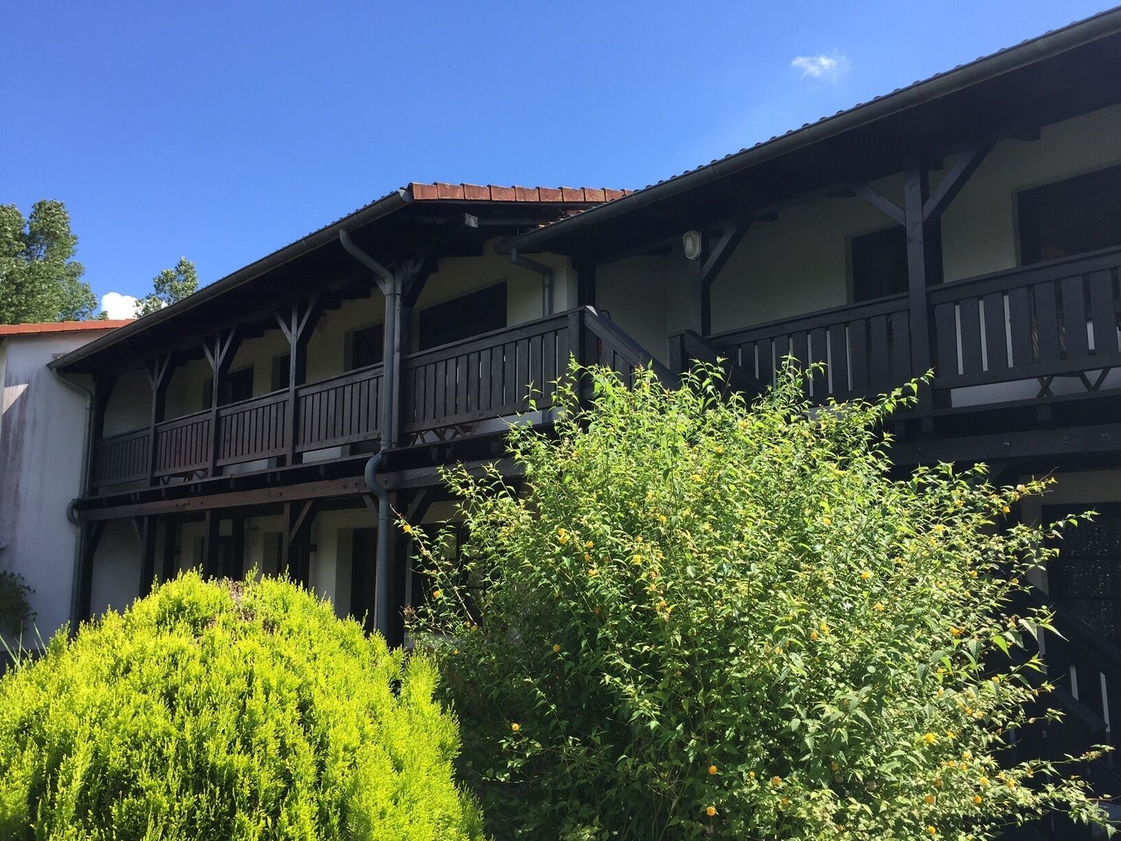 Un bâtiment doté d’un balcon, avec un arbre au premier plan.