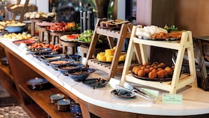 Een buffet met diverse gerechten, waaronder Vietnamese varkensham, gepresenteerd op een toonbank met meerdere aanzitpunten.