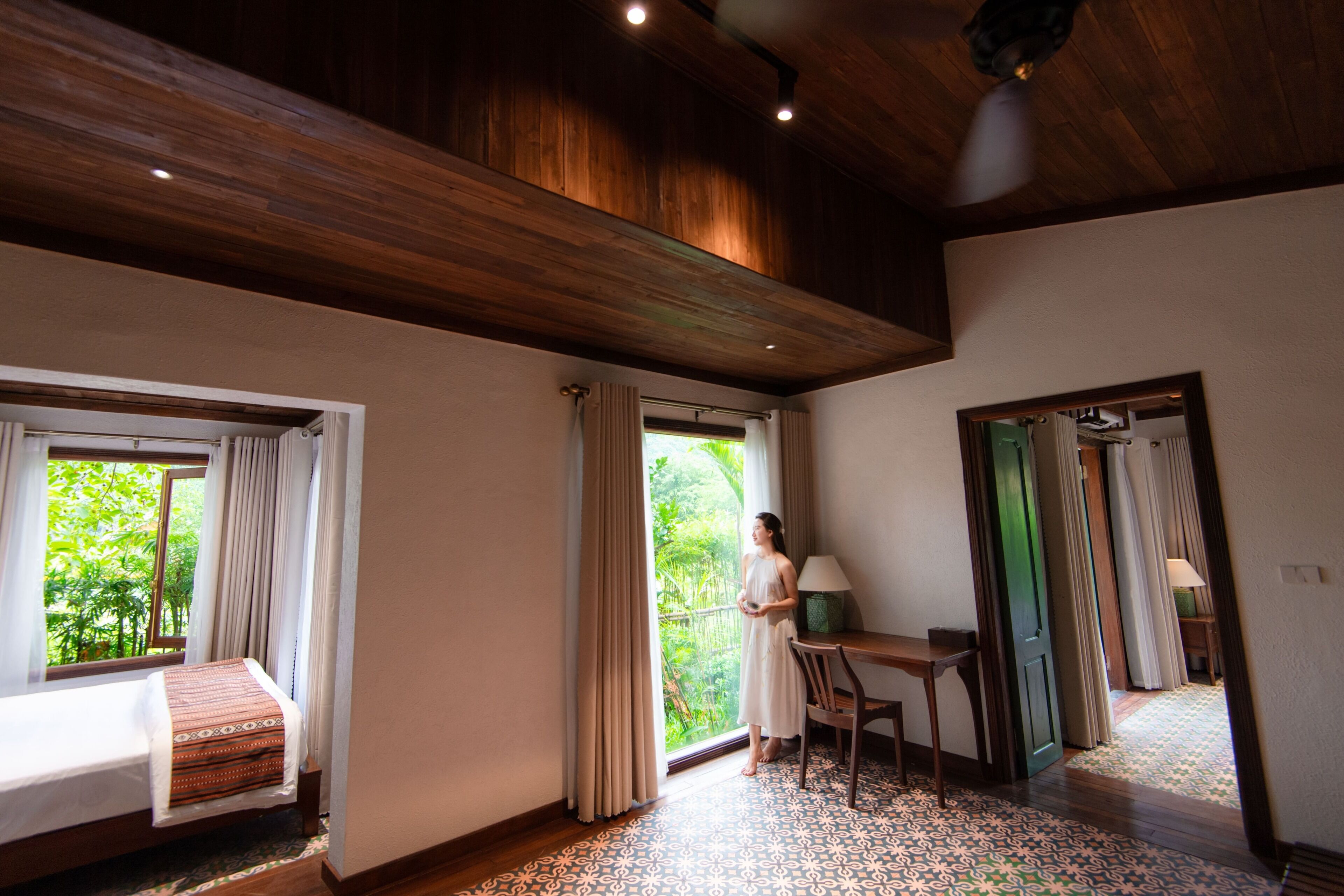 Una habitación con cama, escritorio y vistas al verdor exterior.