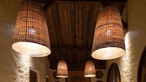 Een gezellig interieur met rieten meubels, een patroon vloer en houten balken aan het plafond.