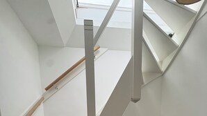 Eine weiße Treppe mit Oberlicht darüber, Holzhandläufen und einem Teppichabgang.