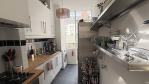 Eine moderne Küche mit weißen Schränken, einer Holzarbeitsplatte, einem eingebauten Backofen und einer Edelstahl-Dunstabzugshaube. Ein Fenster sorgt für natürliches Licht und bietet einen Ausblick ins Freie.