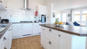 Une cuisine moderne avec des meubles blancs, une hotte en acier inoxydable et un plan de travail en bois.
