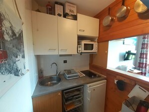 A compact kitchen with a microwave, sink, and a small refrigerator.