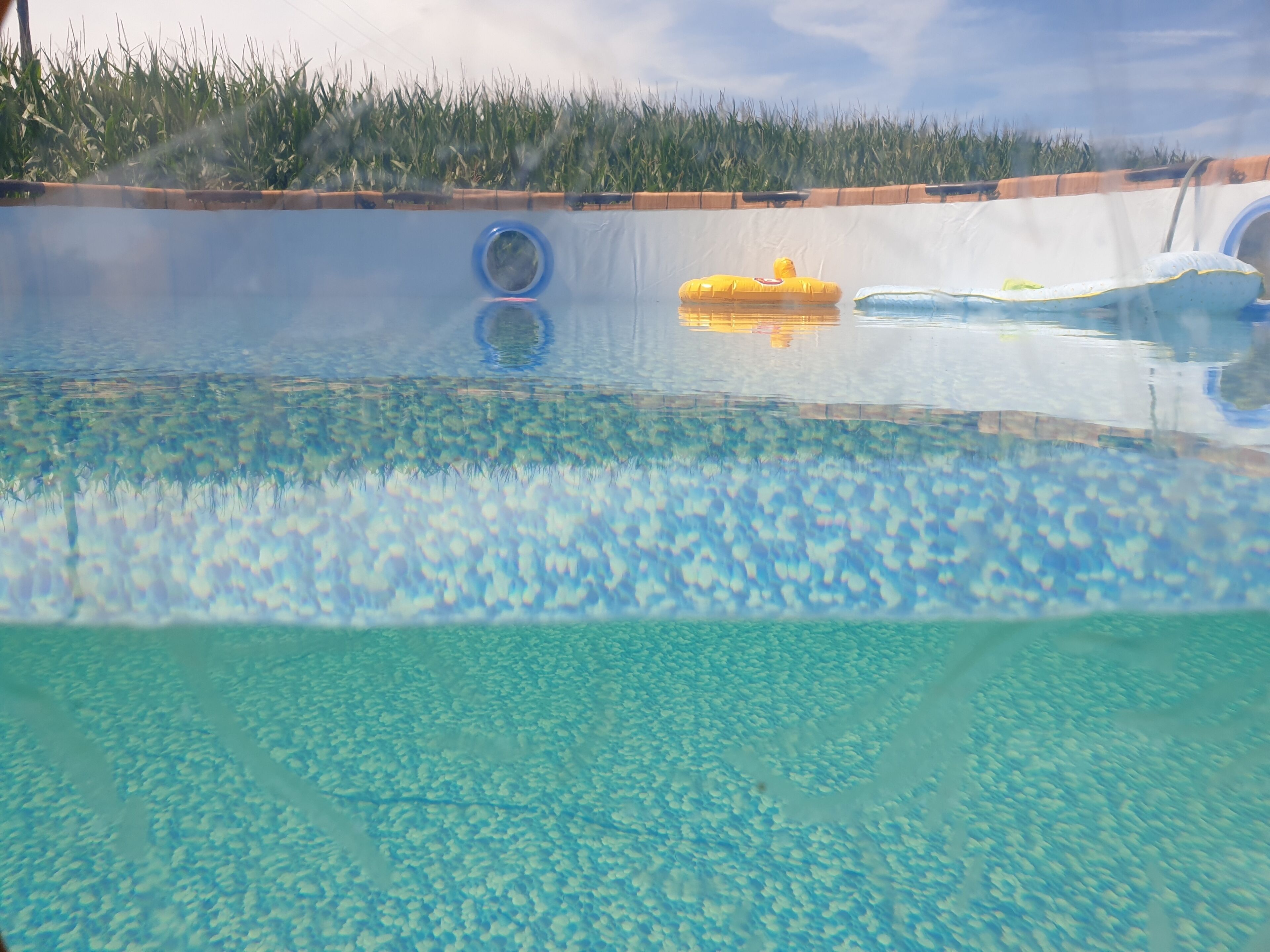 A swimming pool with clear water, a blue circular object, and a yellow inflatable toy.