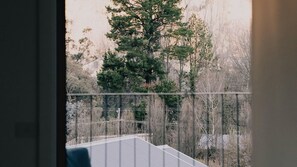 A balcony with a view of a forested area and a building in the background.