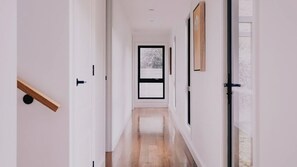 A hallway with a wooden floor, white walls, and a door at the end.