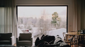 A living room with a sofa, armchair, and a dining table with chairs. - Berghaus Bright - Where design meets the mountains - (Bright)
