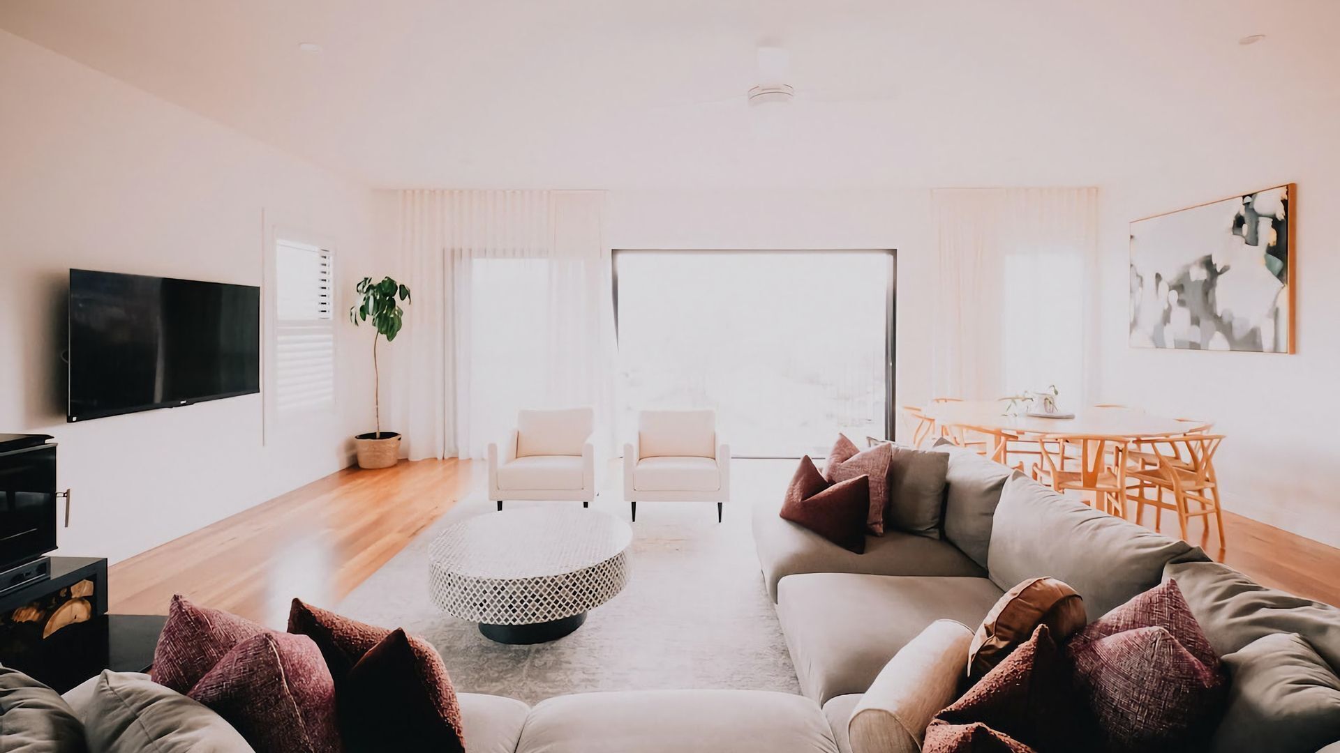 Un salon moderne avec un canapé, des fauteuils, une table basse et un téléviseur.
