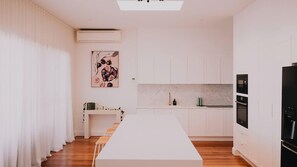 A modern kitchen with white cabinetry, a marble countertop, and a black refrigerator.