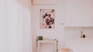 A minimalist kitchen with a white cabinet, a marble countertop, and a wall-mounted air conditioner. - Berghaus Bright  - Where design meets the mountains - (Bright)