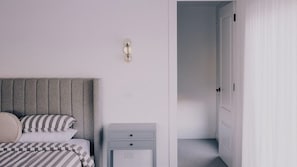 A bedroom with a bed, a bedside table, a nightstand, and a door. - Berghaus Bright - Where design meets the mountains - (Bright)