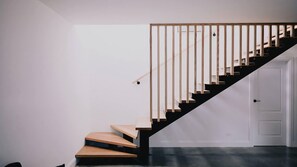 A staircase with wooden steps and a black handrail, leading to a white door.