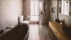 A modern bathroom with a bathtub, toilet, and shower area.