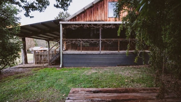 Ein Holzhaus mit überdachter Veranda und einer Metalttür.
