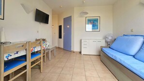 A room with a bed, a desk, a chair, a television, a cabinet, and a door.