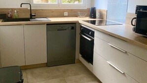 A modern kitchen with a dishwasher, oven, and microwave. - très bel F3 avec balcon (Amélie-les-Bains-Palalda)