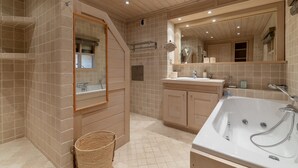 Ein modernes Badezimmer mit einer Standbadewanne, einem großen Spiegel und einem Holzkosmetikschrank.