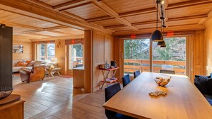 Eine geräumige Holzhütte mit Essbereich, einer Couch und einer Küchenzeile.