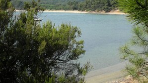 A coastal landscape with a beach, clear water, and forested hills in the background. - Chalet in Bormes-les-Mimosas with terrace (Bormes-les-Mimosas)